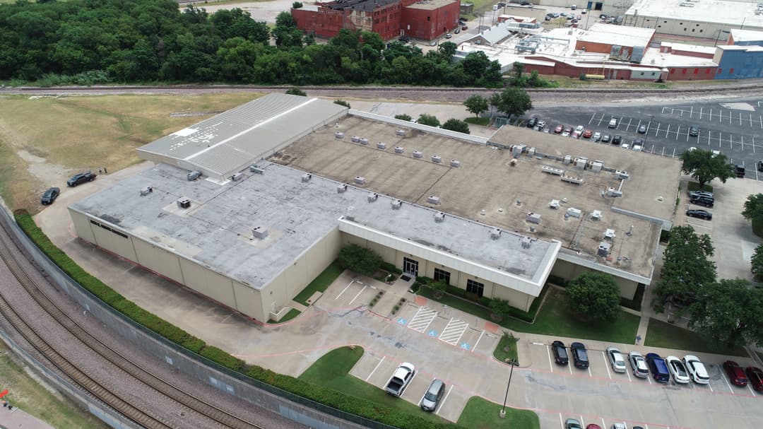 Aerial view of a commercial building with a flat roof and surrounding parking lot.