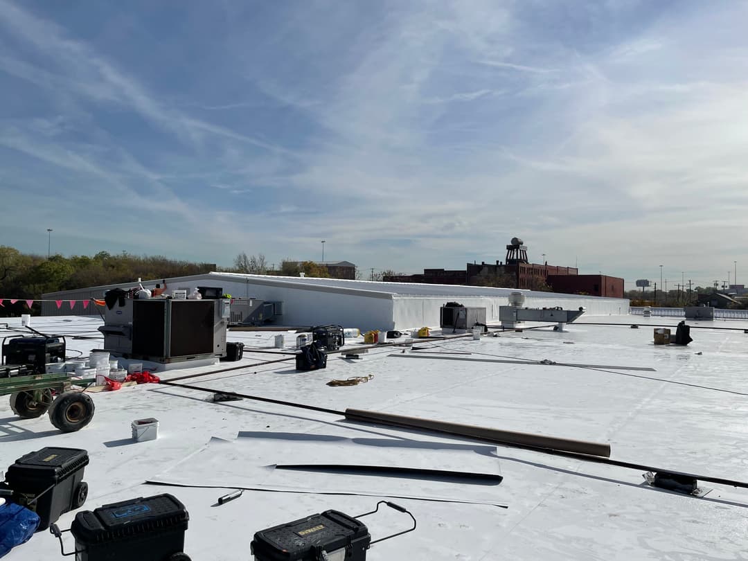 Roof renovation project with equipment, tools, and a clear blue sky in the background.