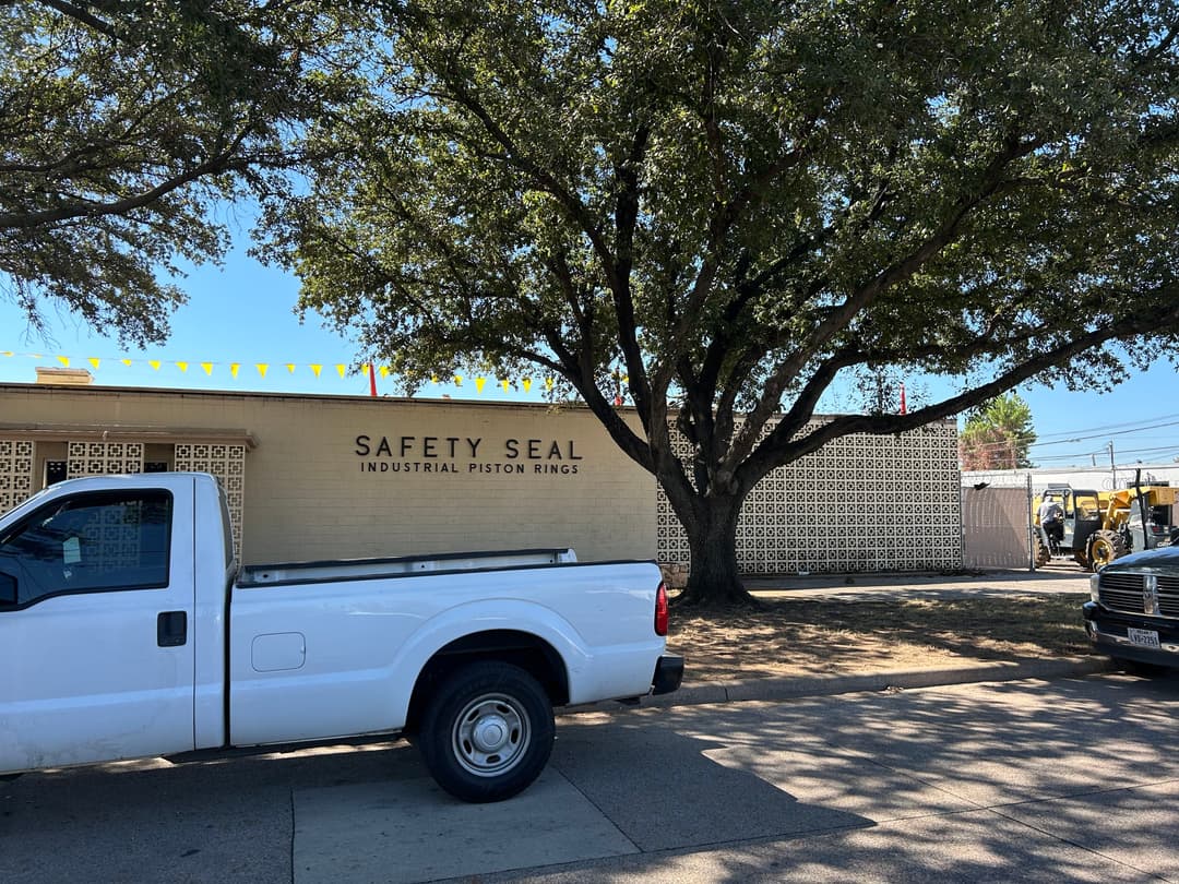White truck parked in front of Safety Seal Industrial Piston Rings building with trees.