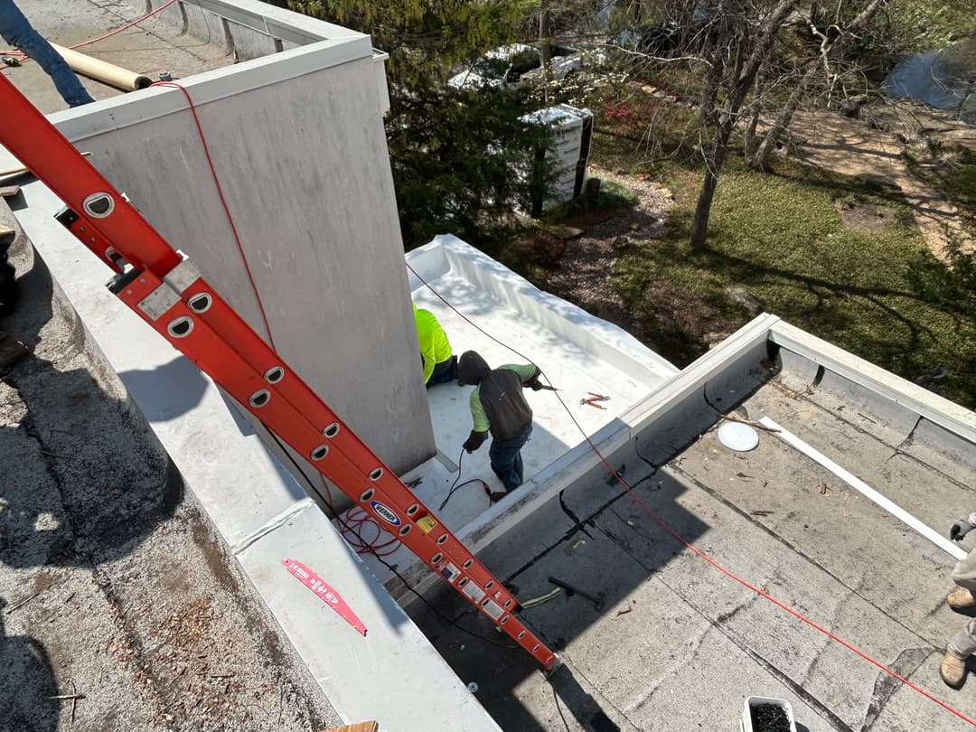 Construction worker on rooftop installing materials with a level and tools nearby.