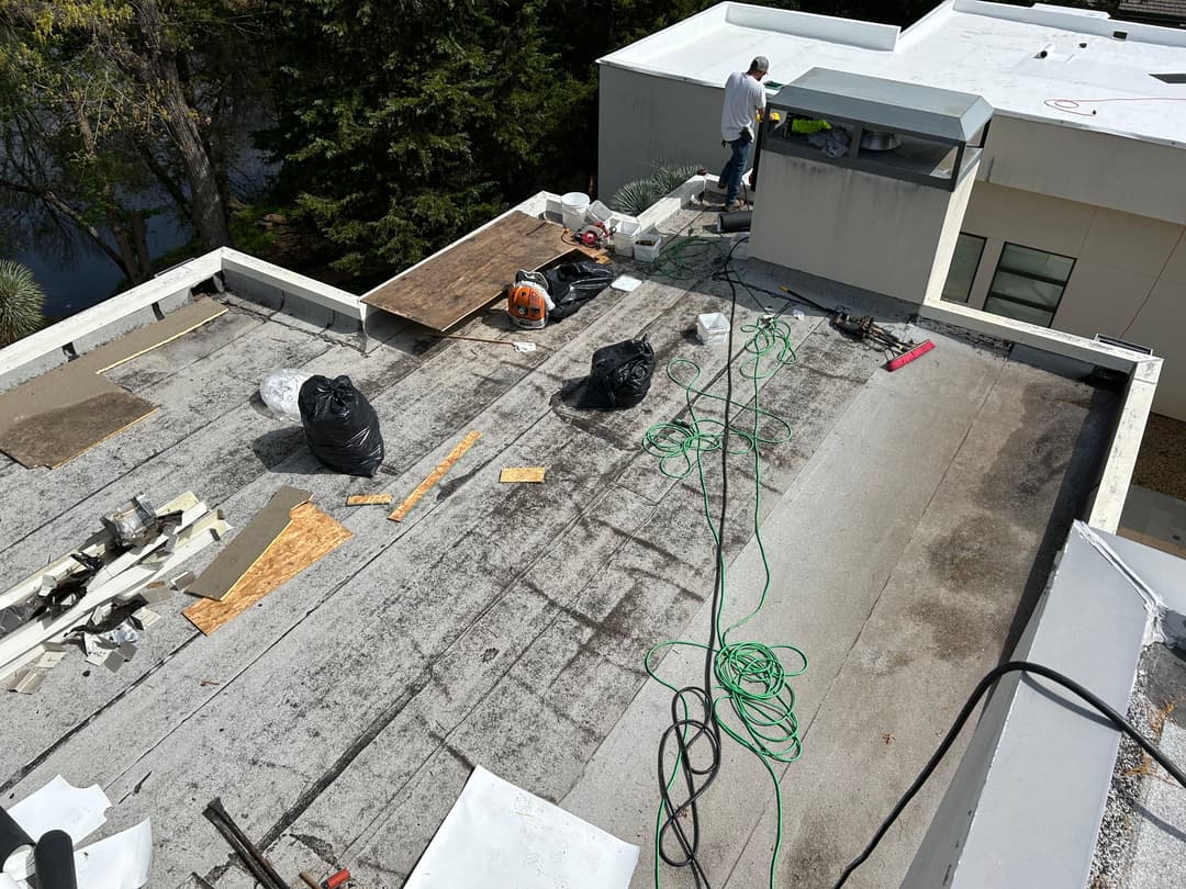 Rooftop construction with workers, tools, and materials for repair or maintenance.