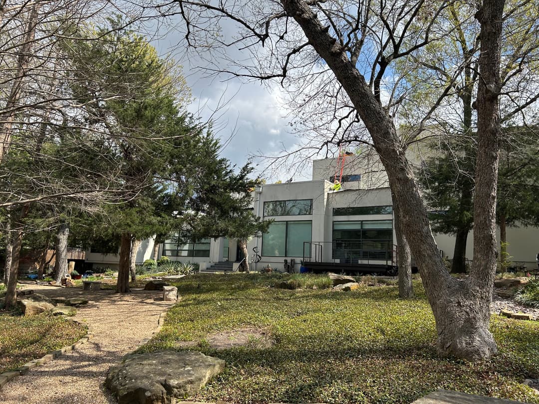 Modern architectural building surrounded by trees and a landscaped garden path.