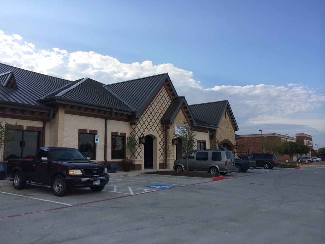 Shopping center exterior with parking, modern design, and clear blue sky.