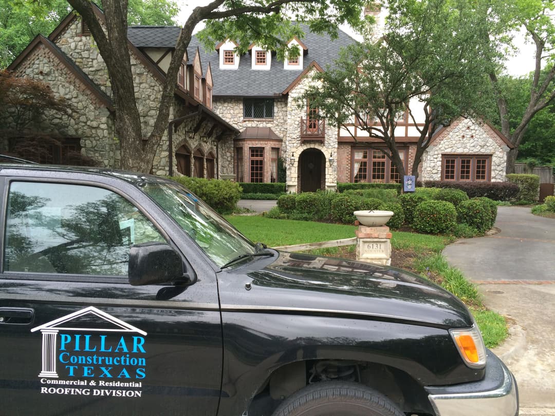Stone house with landscaping and Pillar Construction Texas vehicle in front.