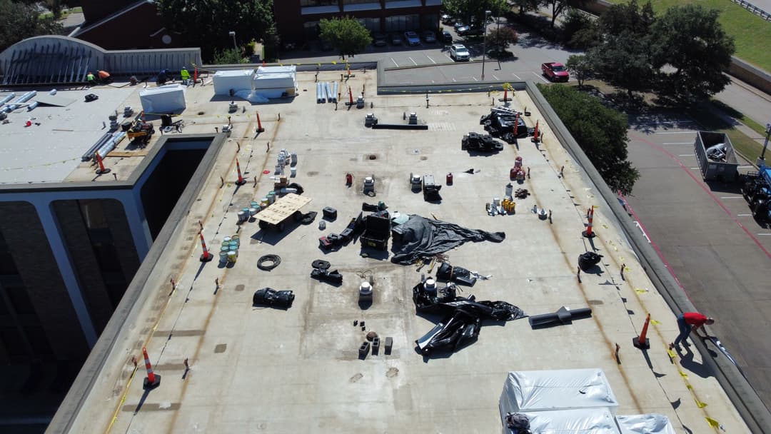 Aerial view of a flat roof with construction materials and workers on site.