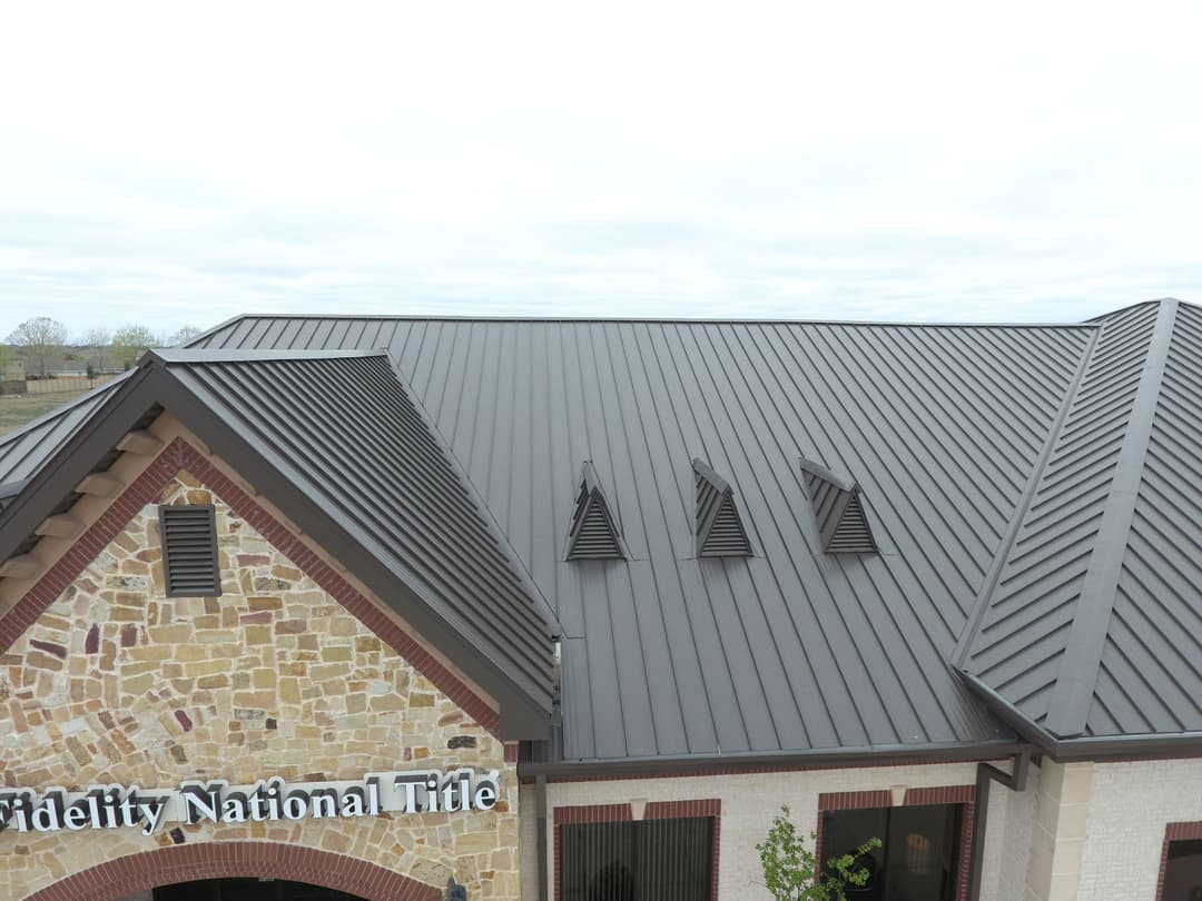 Metal roof of Fidelity National Title building with three ventilation features.