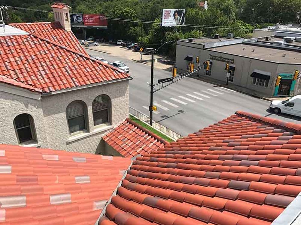 View of rooftops with red tiles overlooking a busy street and commercial buildings.