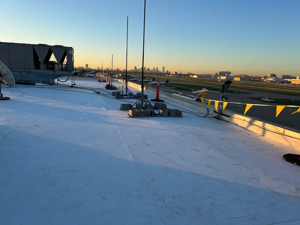 Rooftop view of an airport at sunrise, showcasing city skyline and construction equipment.