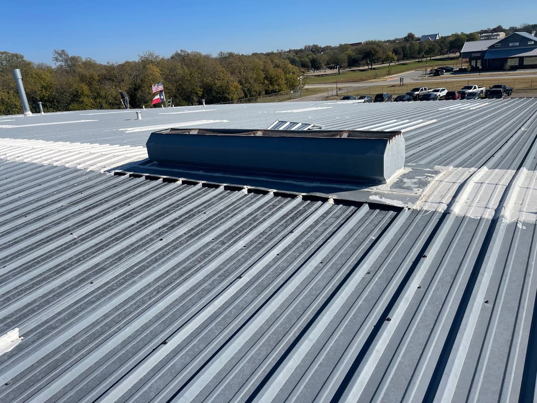 Metal roof with ventilation structure and clear blue sky in the background.